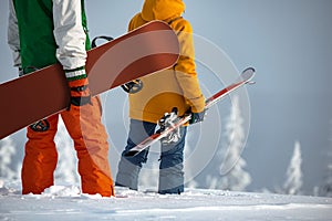 Unrecognized skier and snowboarder couple stands at mountain top