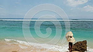 Unrecognized tourist relaxing on the beach. Woman with oversized hat