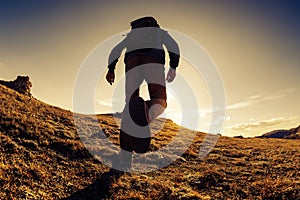 Unrecognized traveler hiker walks in mountains at sunset