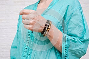 Unrecognized woman in ethnic clothes showing hand made bracelets with wooden beads on her hand