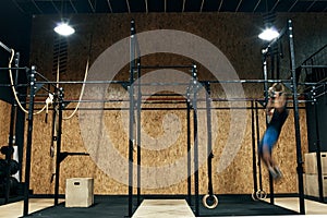 Unrecognized young sportsmen doing pull-ups in functional training gym, motion blurred. Gym equipment background concept