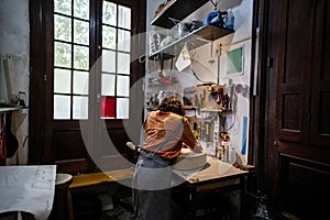 Unrecognized young woman in her luthier workshop.