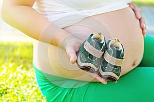 Unrecognnizable Pregnant Woman playing with baby boy shoes