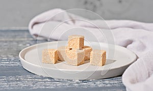 unrefined brown cane sugar cubes on cement plate. stack of natural sweetener for healthy meal