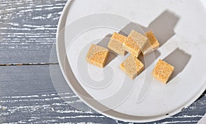 unrefined brown cane sugar cubes on cement plate. stack of natural sweetener for healthy meal, top view