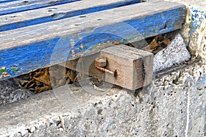 Unreliable fastening of a wooden board with a nail bent around a metal bolt