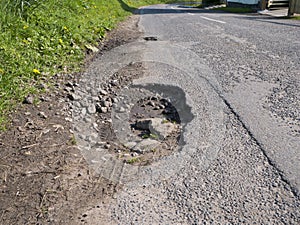 Unrepaired surface damage to tarmac on a rural road