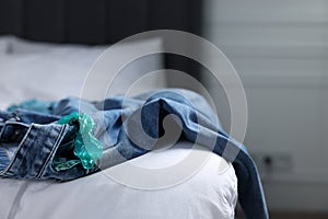 Unrolled condom and jeans on bed in bedroom. Safe sex