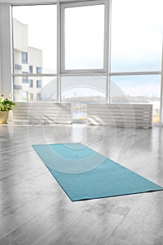 Unrolled light blue yoga mat on floor