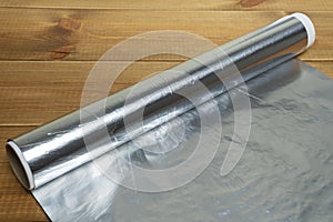 Unrolled roll of aluminum foil for baking on wooden table