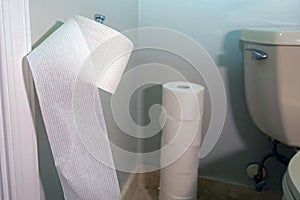 An unrolled roll of toilet paper in corner bathroom