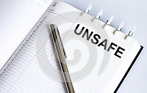 UNSAFE on the short note texture background with pen
