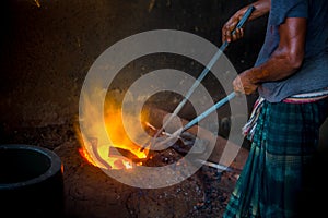 Unsafe worker hands. A local steel machine parts making yard worker melting scrap on hot furnace