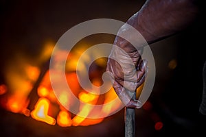 Unsafe worker hands. A local steel machine parts making yard worker melting scrap on hot furnace