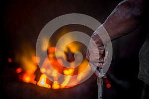 Unsafe worker hands. A local steel machine parts making yard worker melting scrap on hot furnace