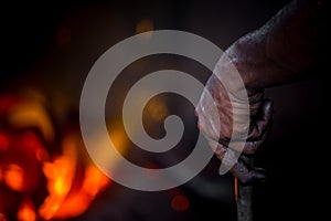 Unsafe worker hands. A local steel machine parts making yard worker melting scrap on hot furnace