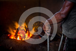 Unsafe worker hands. A local steel machine parts making yard worker melting scrap on hot furnace