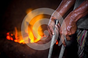 Unsafe worker hands. A local steel machine parts making yard worker melting scrap on hot furnace