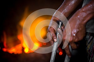 Unsafe worker hands. A local steel machine parts making yard worker melting scrap on hot furnace