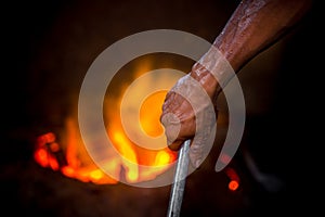 Unsafe worker hands. A local steel machine parts making yard worker melting scrap on hot furnace