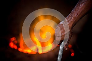 Unsafe worker hands. A local steel machine parts making yard worker melting scrap on hot furnace