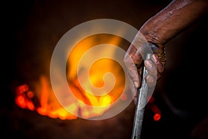 Unsafe worker hands. A local steel machine parts making yard worker melting scrap on hot furnace