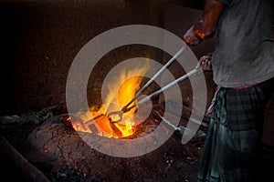 Unsafe worker hands. A local steel machine parts making yard worker melting scrap on hot furnace