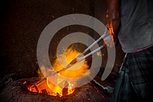 Unsafe worker hands. A local steel machine parts making yard worker melting scrap on hot furnace