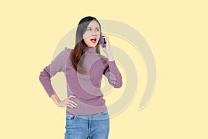 A unsatisfied Asian woman is talking on the phone aggressively. isolated yellow background