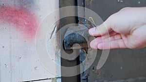 Unscrewing the old blockage lock on the iron door of the black garage. Protection against intrusion and theft, close-up