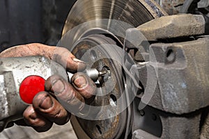 Unscrewing the old brake disc from the car with a pneumatic screwdriver.