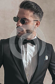 Unshaved businessman with bowtie and sunglasses looking to side