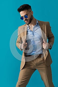 Unshaved businessman with retro sunglasses adjusting suit