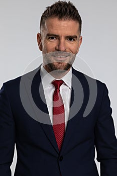 Unshaved businessman in suit in his forties smiling and posing