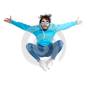Unshaved casual guy in hoodie jumping in the air and opening arms