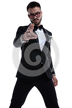 Unshaved dramatic man in tuxedo making gun gesture