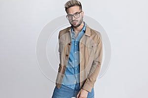 Unshaved fashion man in denim shirt holding hand in back pocket