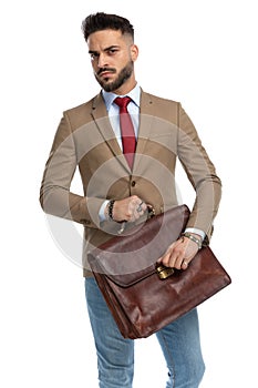 Unshaved guy with red tie holding and opening suitcase