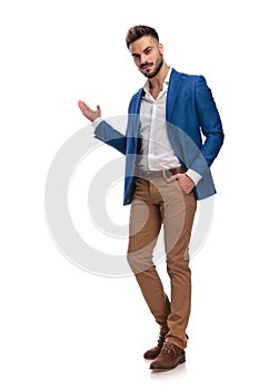 Unshaved guy in suit greeting with hand in pocket