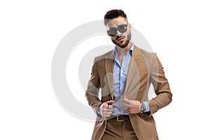 Unshaved handsome guy with sunglasses arranging suit