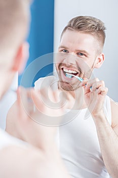 Unshaved man brushing his teeth