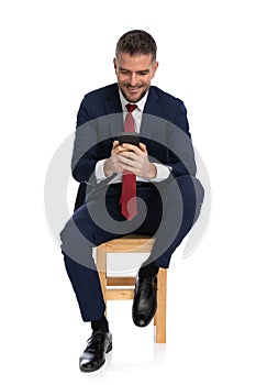 Unshaved man in his forties holding mobile and typing messages