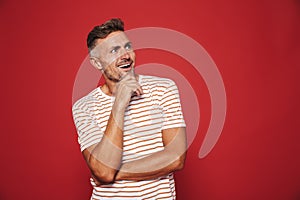 Unshaved man in striped t-shirt touching chin and looking aside