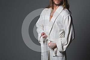 Unshaved man tying mild housecoat