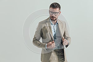 Unshaved middle aged businessman with glasses arranging suit