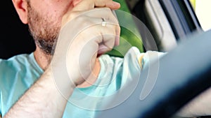 Unshaven man drinks coffee in the car while driving. Rest, increase vigor during the trip concept
