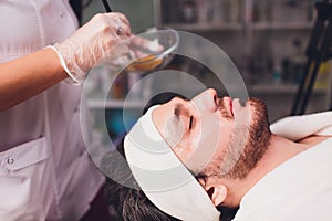 Unshaven man having cosmetic mask in spa salon, top view.