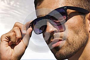 Unshaven man in sunglasses on the background of white architecture, eyewear advertising.