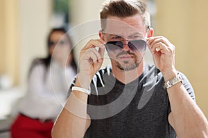 Unshaven man takes off sunglasses close-up portrait