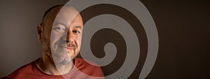 Unshaven middle-aged man, about 40 years old, wearing approachable smile and ordinary look in close-up shot. Banner